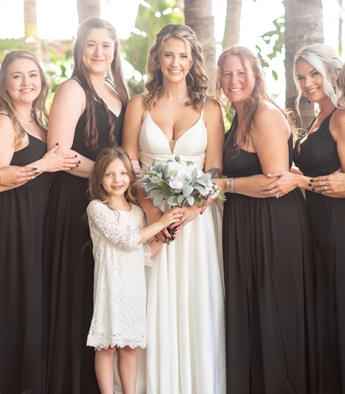 4 bridesmaids and a flower girl with a bride in front of palm trees