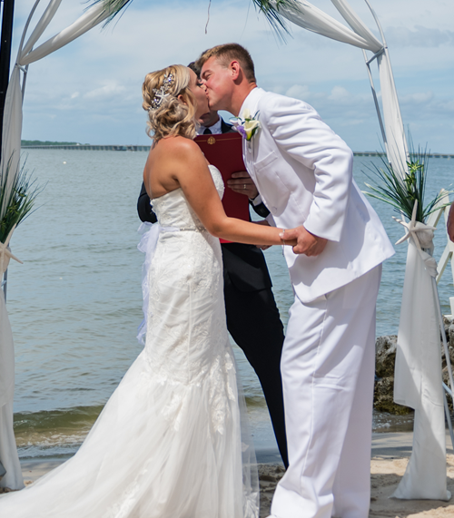 Couple kissing at the altar with the bay in the background