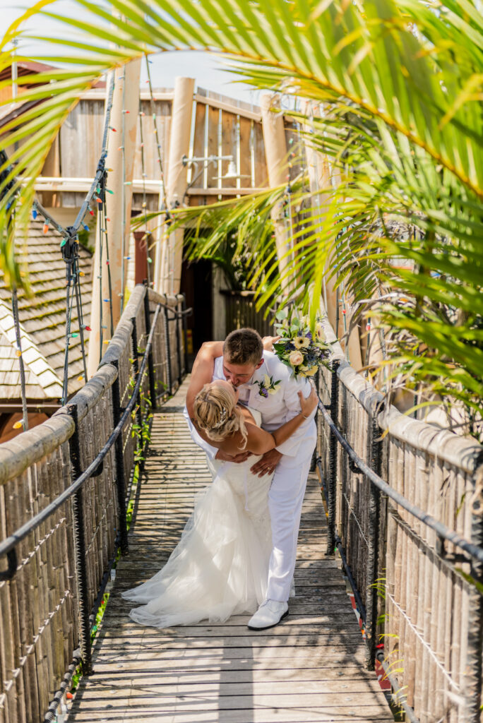 a bride and groom kissing on a bridge