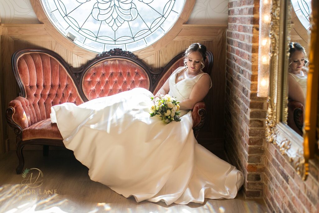 a bride sitting on a red chair in front of a stained glass window