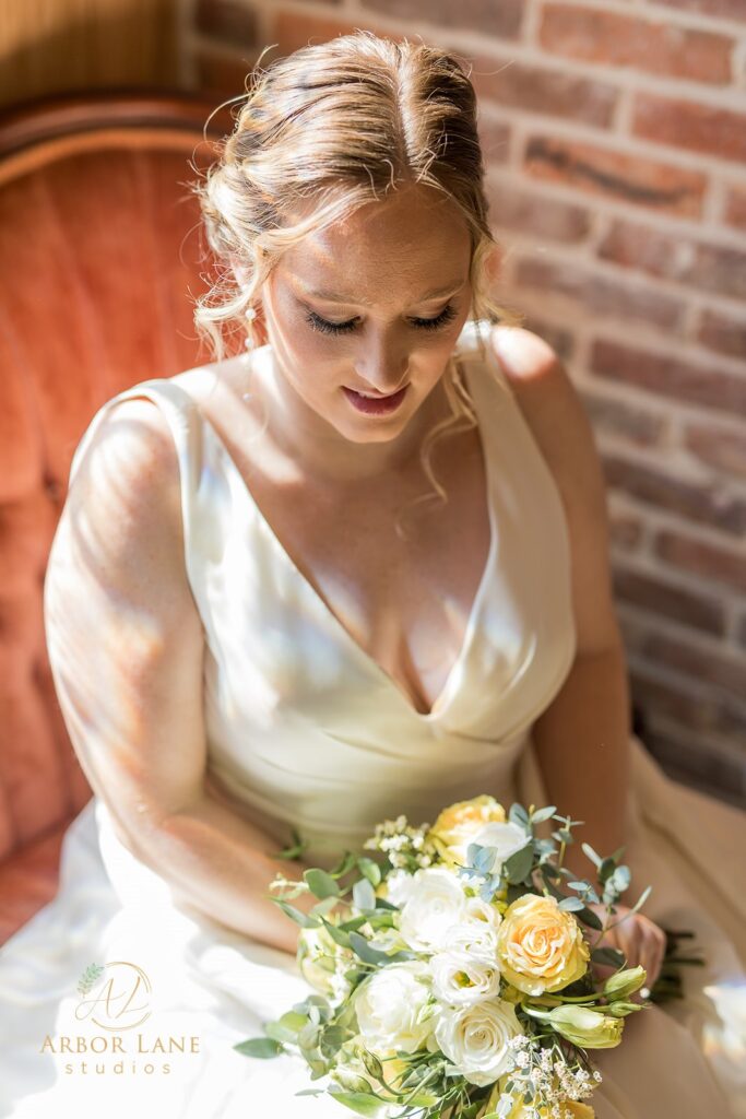 a bride sitting on a bed holding a bouquet of flowers