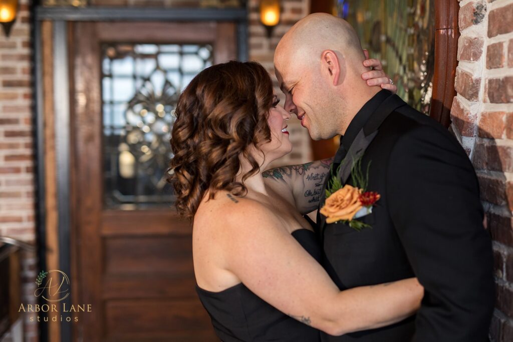 a bride and groom kissing in front of a brick wall