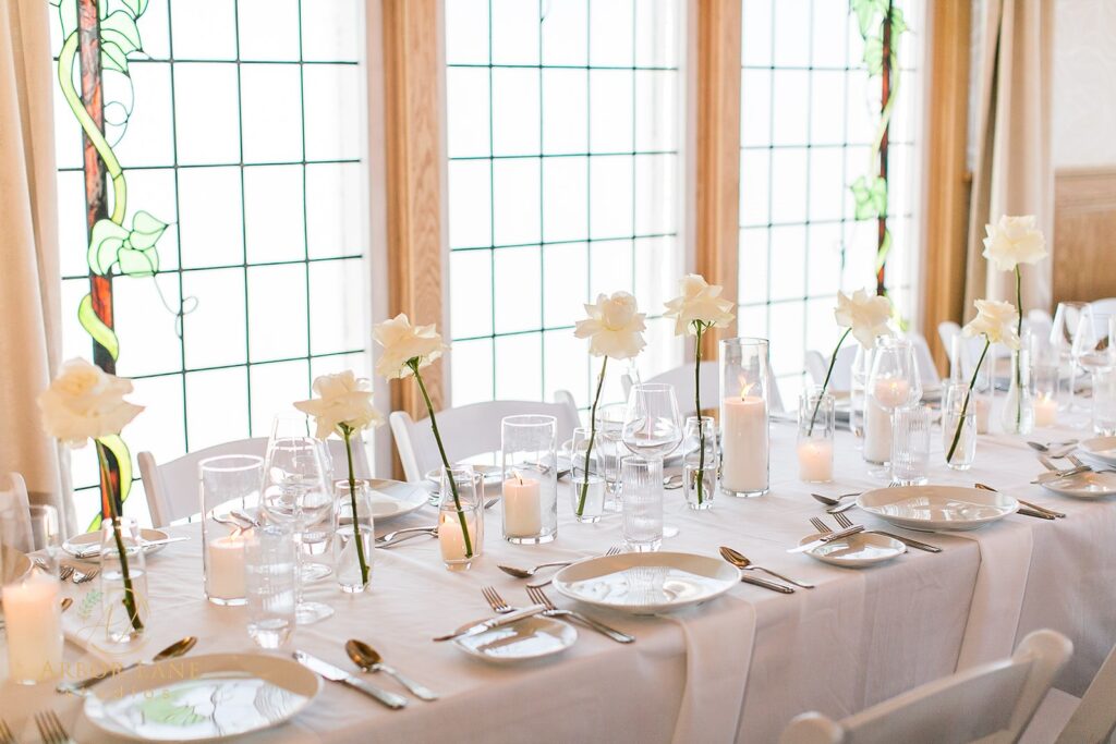 a table set for a formal dinner with white flowers and candles