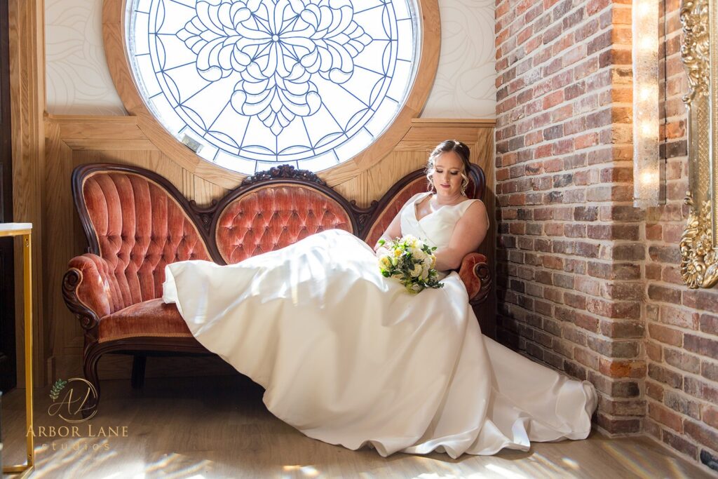 a bride sitting on a chair in front of a stained glass window