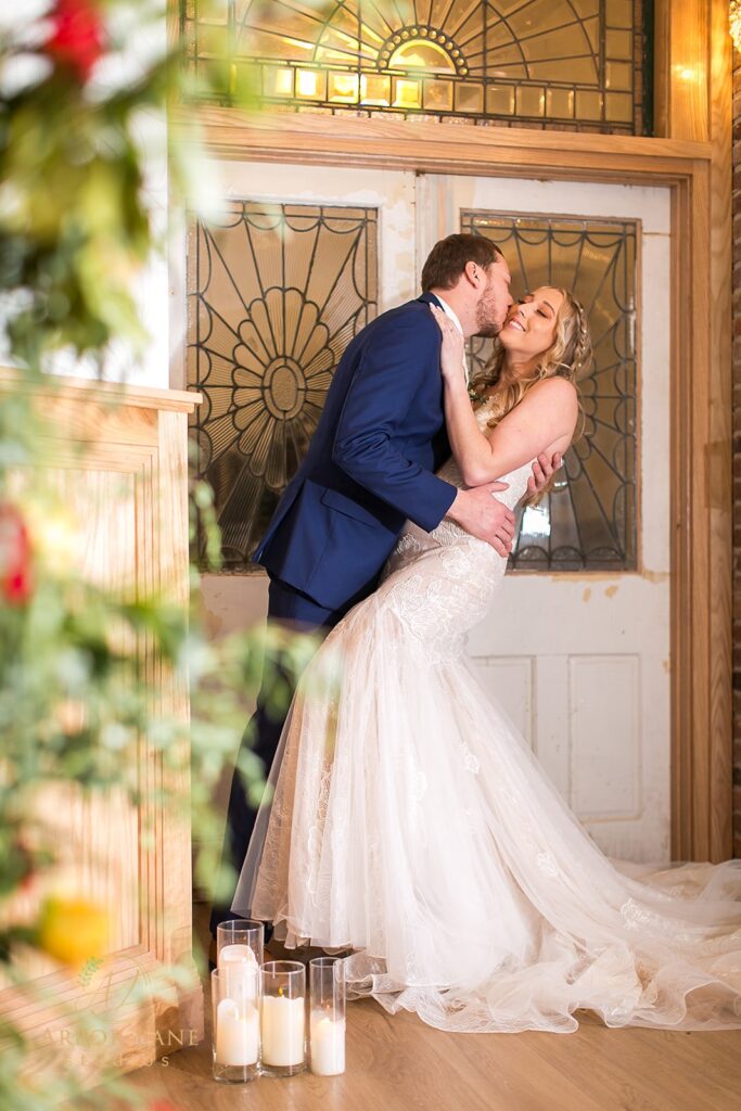 a bride and groom kissing in front of a door