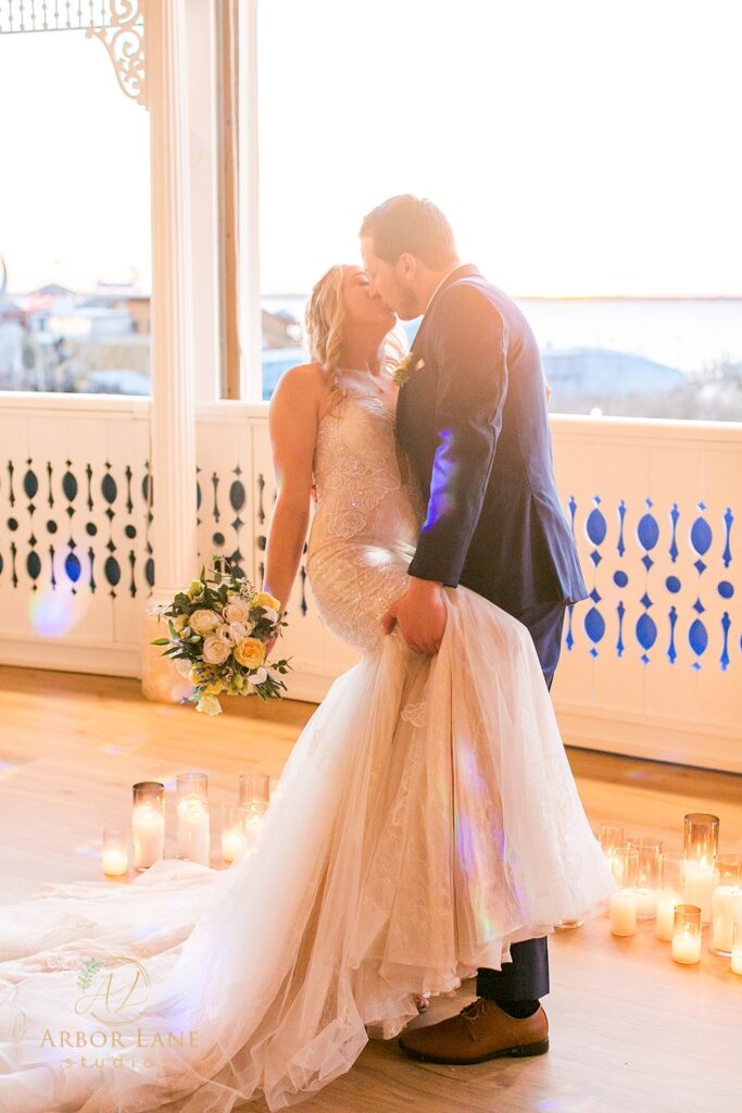 a bride and groom kissing in front of candles