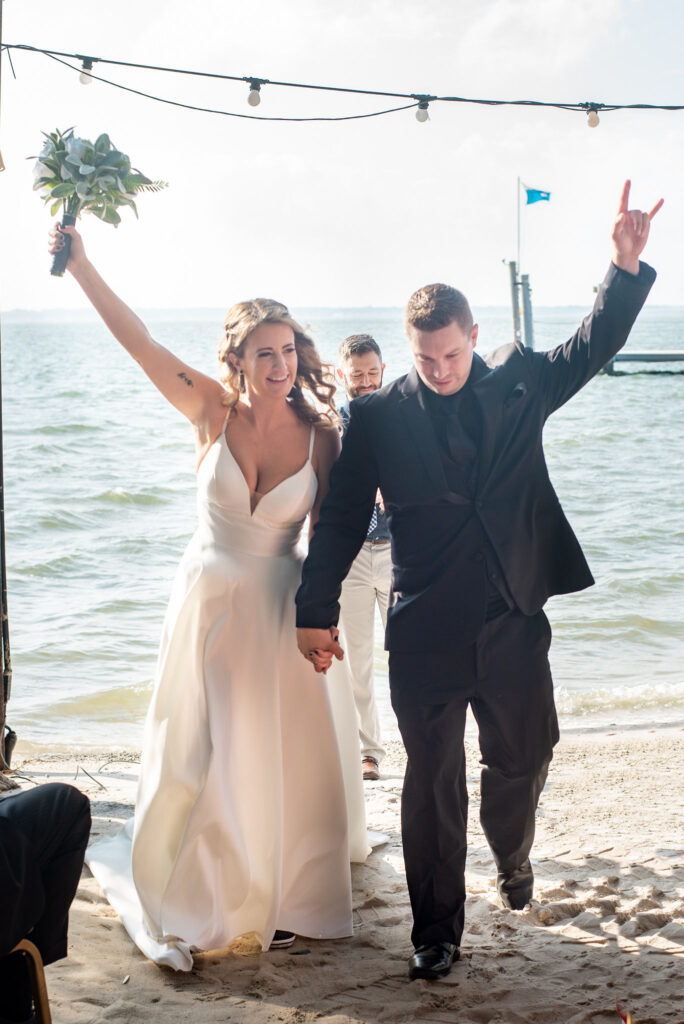 a bride and groom walking down the beach