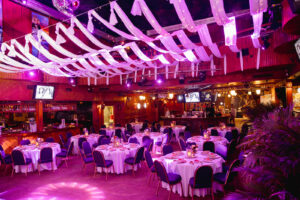 a banquet hall with purple lighting and white tablecloths