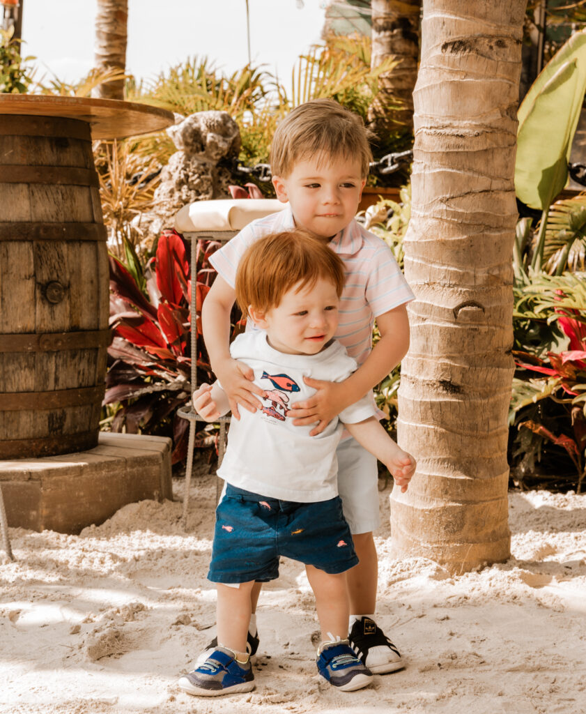 two young boys standing next to each other in the sand