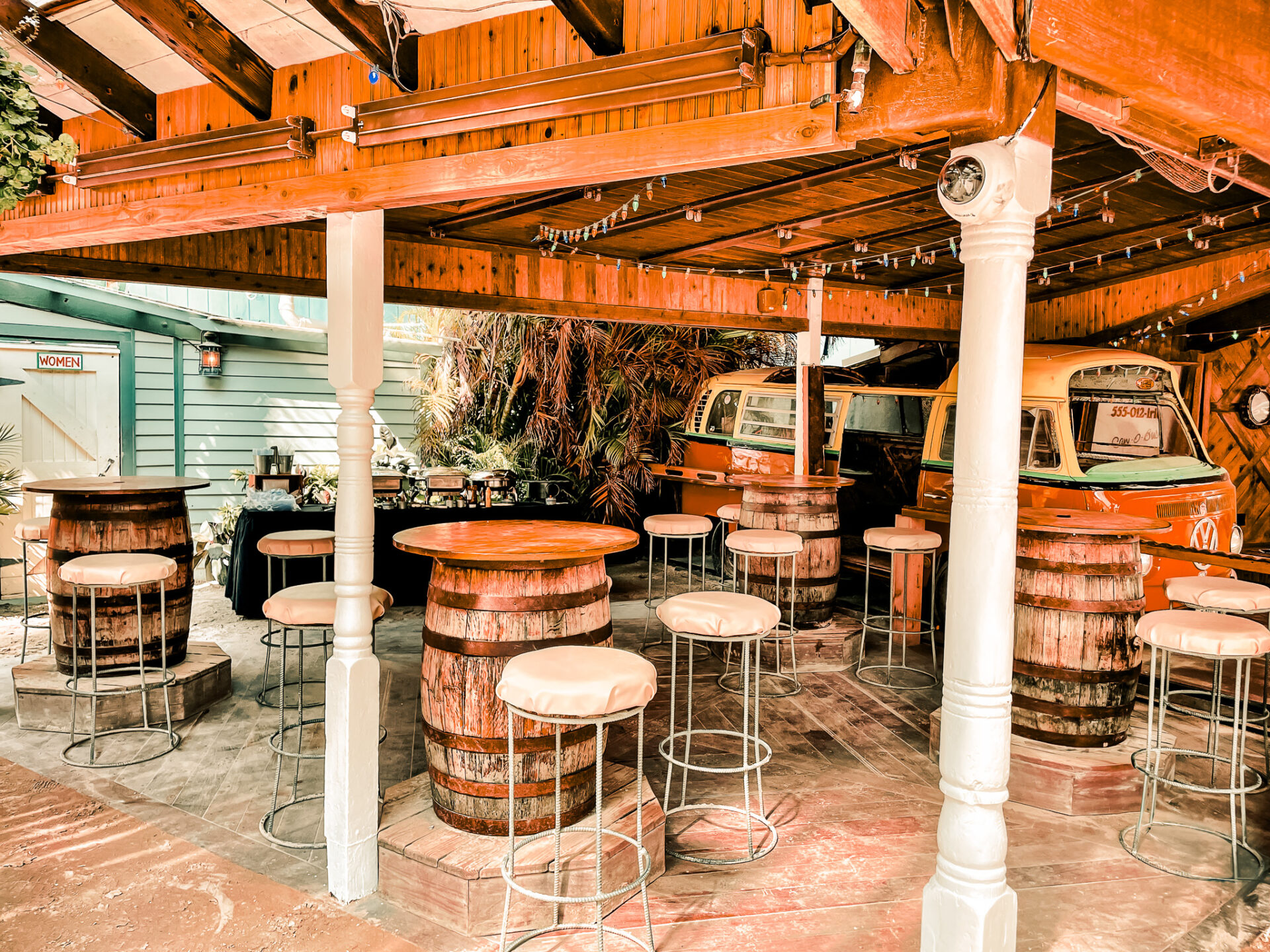 a covered patio with stools and wooden barrels