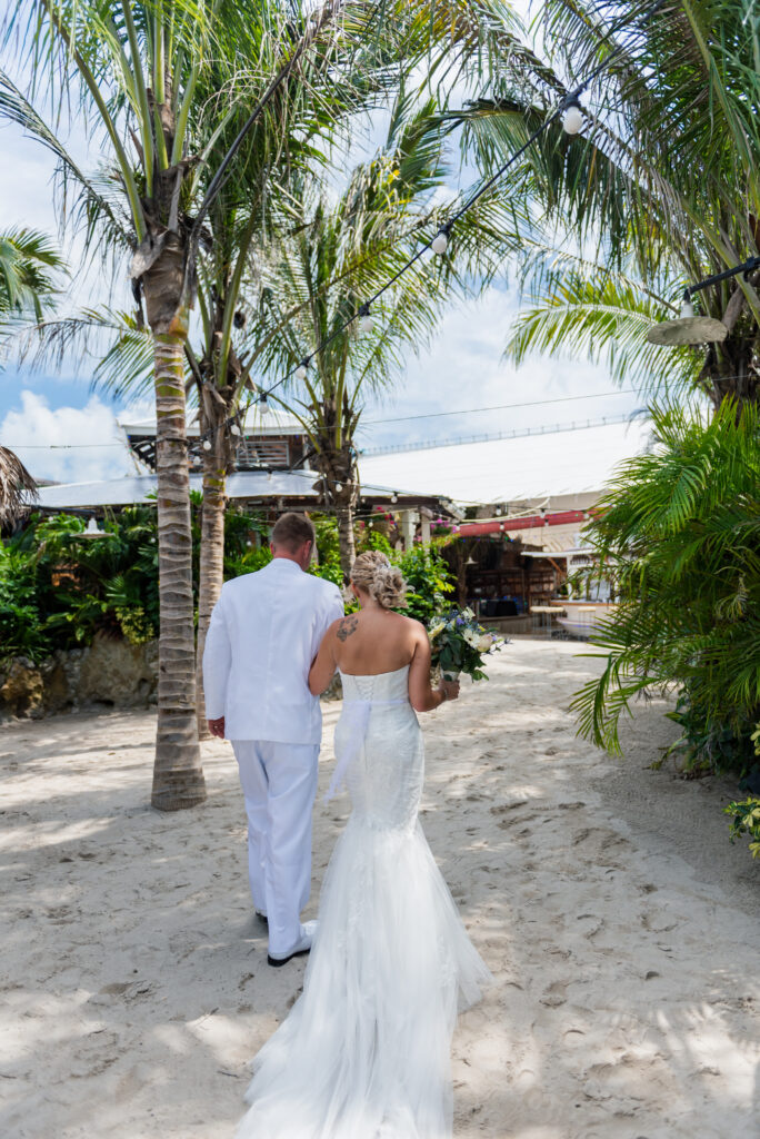 a bride and groom walking down the beach