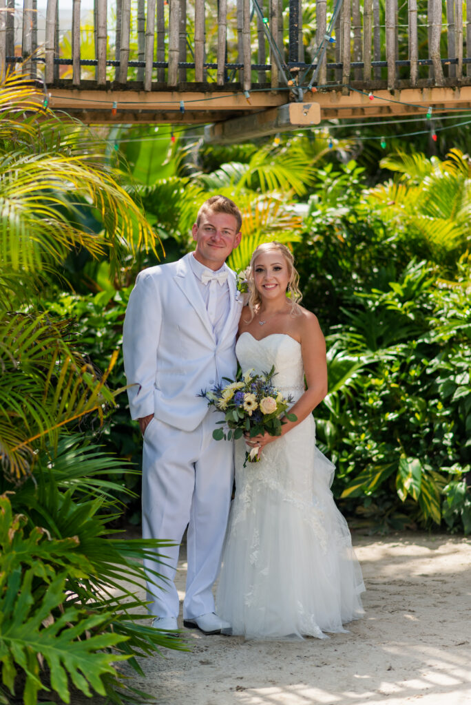 a bride and groom posing for a picture in a tropical setting