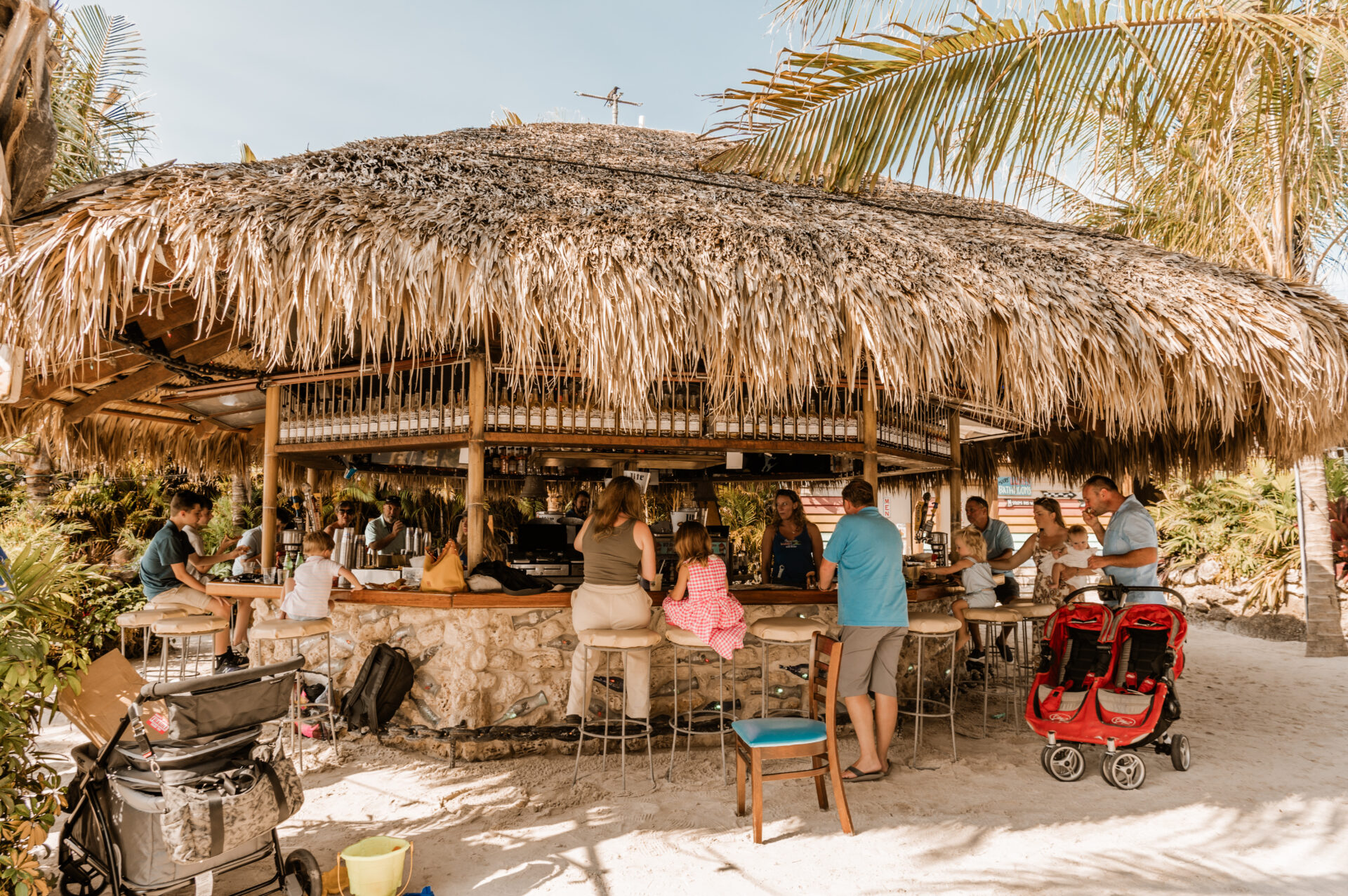 a group of people standing around a bar on the beach