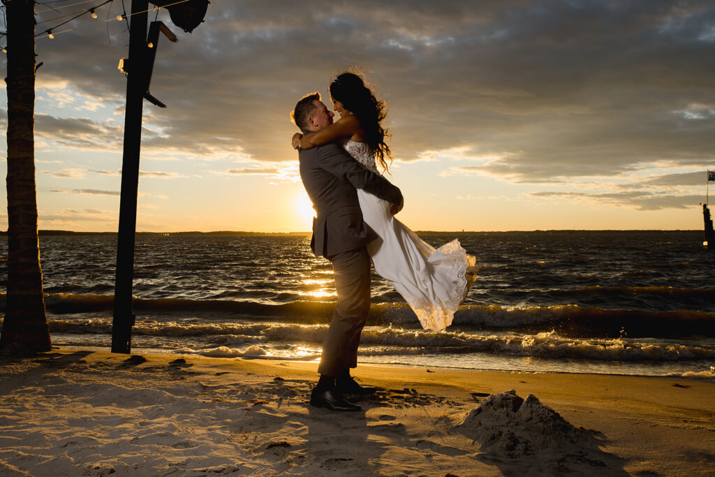 a man holding a woman on the beach at sunset