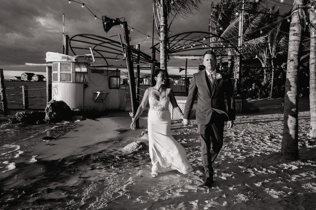 a bride and groom walking on the beach