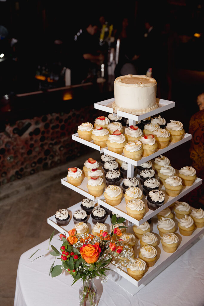 a wedding cake and cupcakes on a table