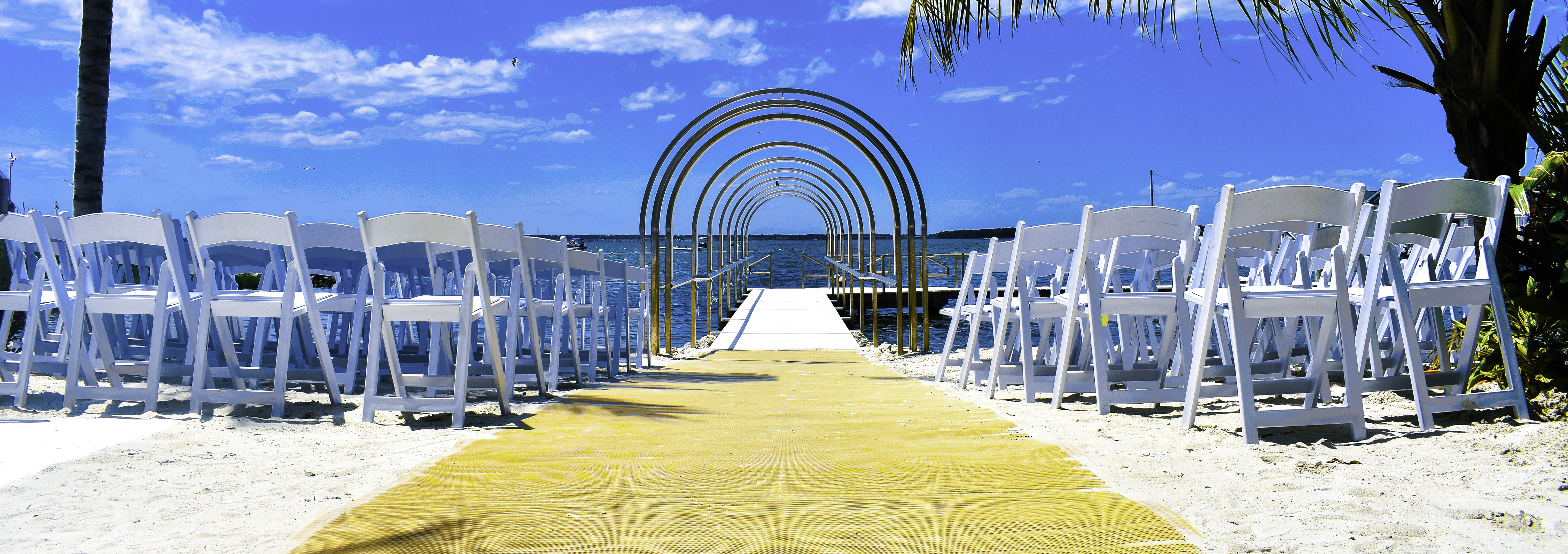 a wedding ceremony on the beach with white chairs